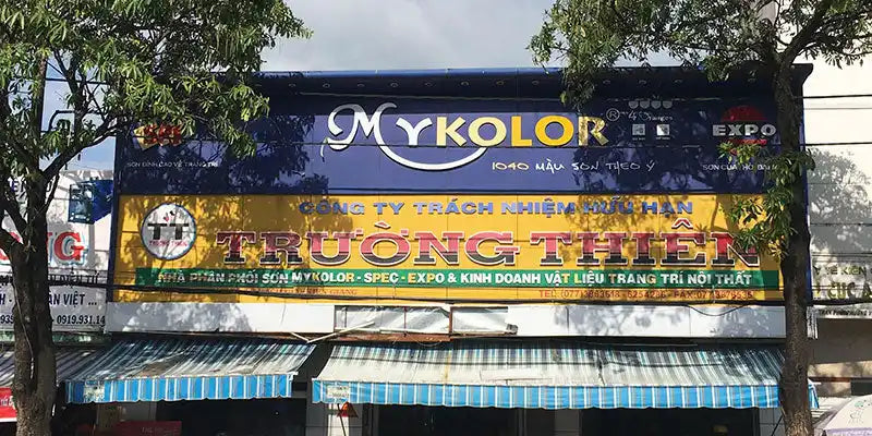 Biển hiệu cửa hàng hiển thị 'MYKOLOR' với thương hiệu màu xanh và vàng.