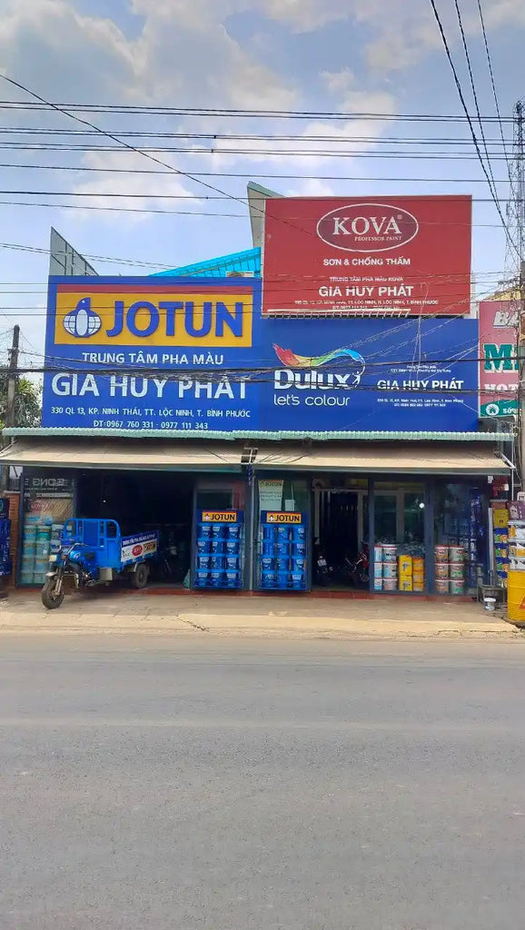 Cửa hàng sơn và phần cứng với bảng hiệu 'KOVA' và 'JOTUN' trên mặt tiền.