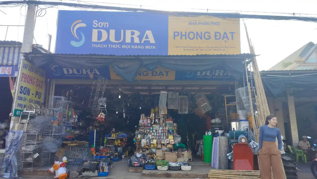 Cửa hàng Việt Nam có bảng hiệu 'DURA' và 'PHONG DAT'.