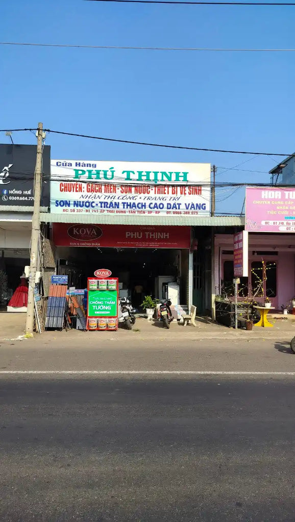 Cửa hàng Việt Nam với biển hiệu 'PHÚ THỊNH' và hàng hóa trưng bày ở lối vào.