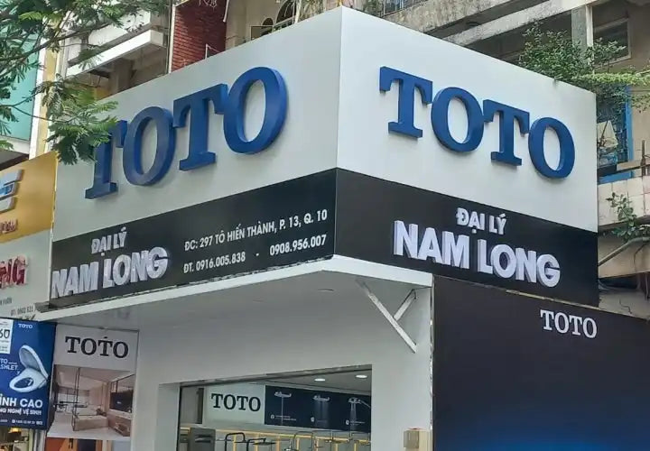 Biển hiệu storefront TOTO với chữ màu xanh trên nền trắng và đen.